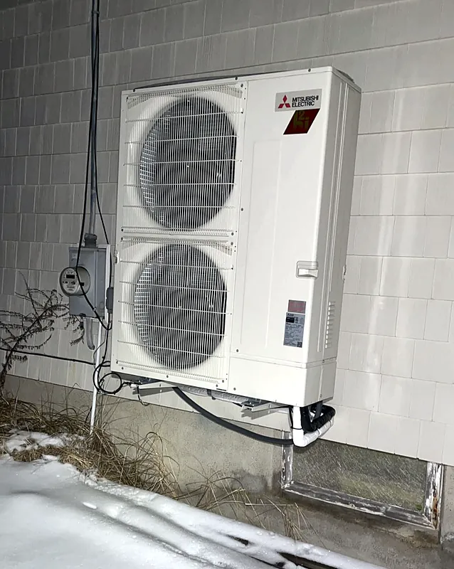 Mitsubishi Electric Hyper-Heat outdoor unit on a wall bracket above the snow